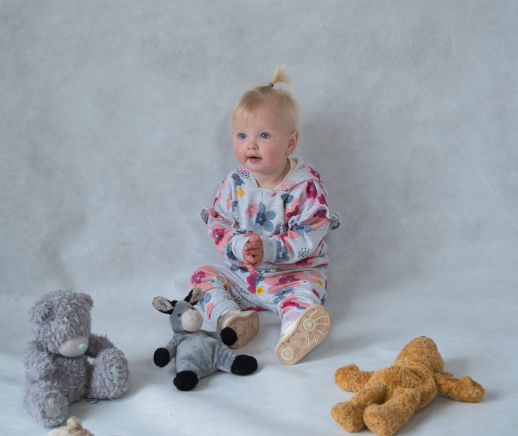 Young child on her first photo shoot surrounded by toys 